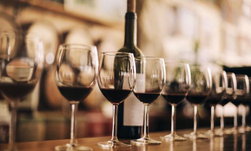 Wine bottle on wooden bar Wine bottle with glasses of red wine on wooden table